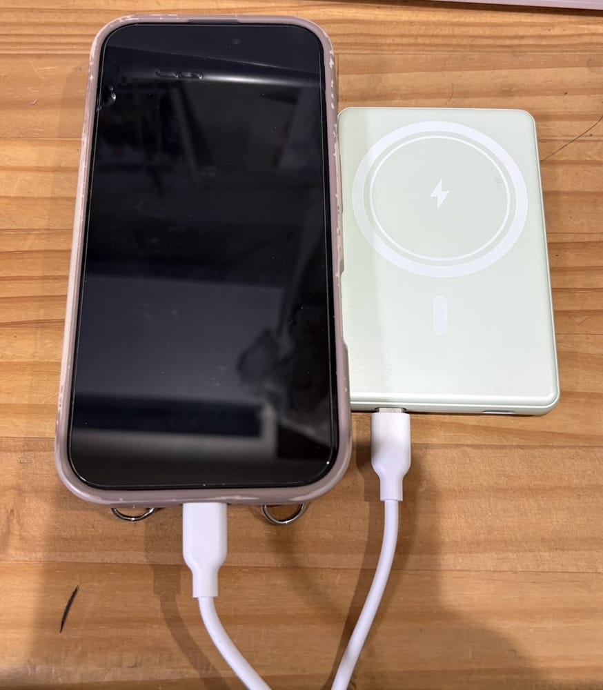 iPhoneと並べたモバイルバッテリーの大きさ比較。スマホより一回り小さいカードサイズで薄い